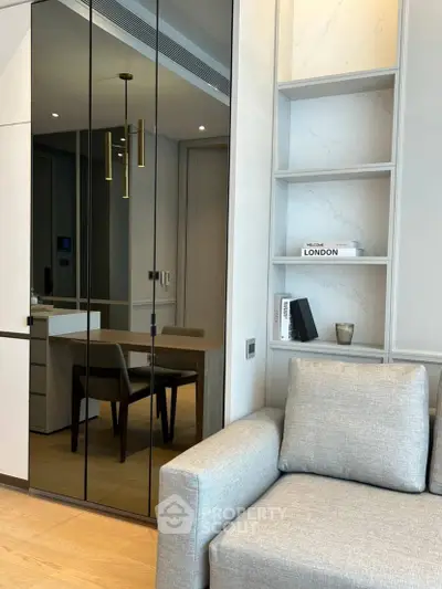 Modern living room with sleek design and mirrored wall, featuring cozy seating and stylish decor.