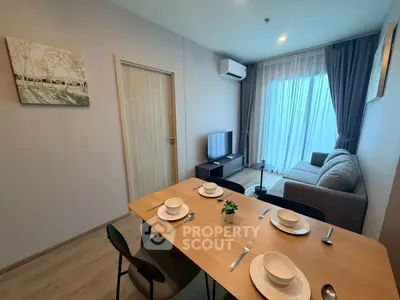 Modern living room with dining area, featuring cozy sofa and large window for natural light.