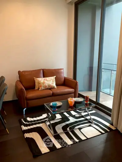 Stylish living room with leather sofa and glass coffee table, featuring a modern balcony view.