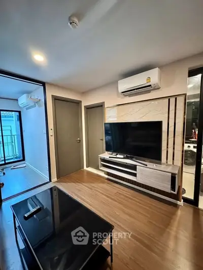 Modern living room with sleek TV setup and air conditioning, featuring wooden flooring and stylish decor.
