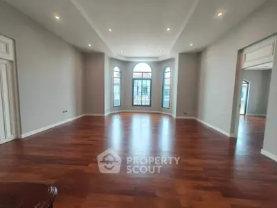 Spacious and elegant living room with hardwood floors and large windows, perfect for natural light.