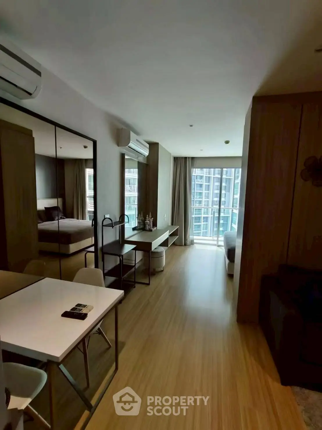 Modern apartment interior with open layout and large windows offering city views.