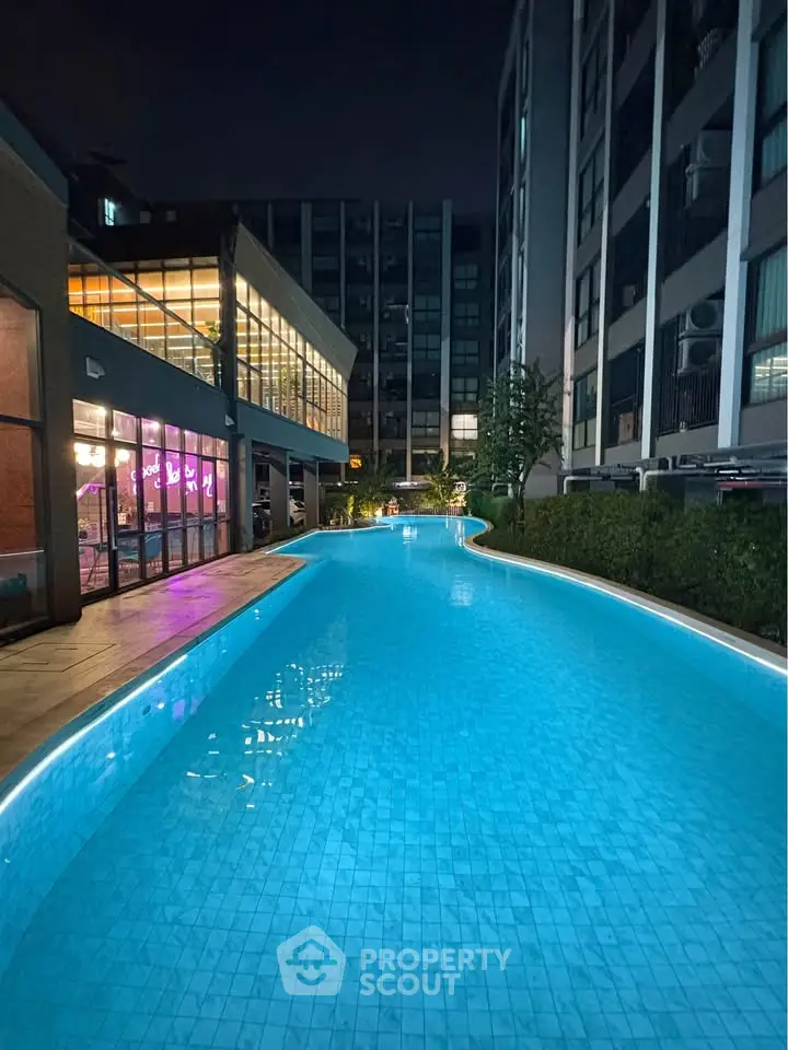 Luxurious night view of a modern apartment complex with a stunning illuminated pool.