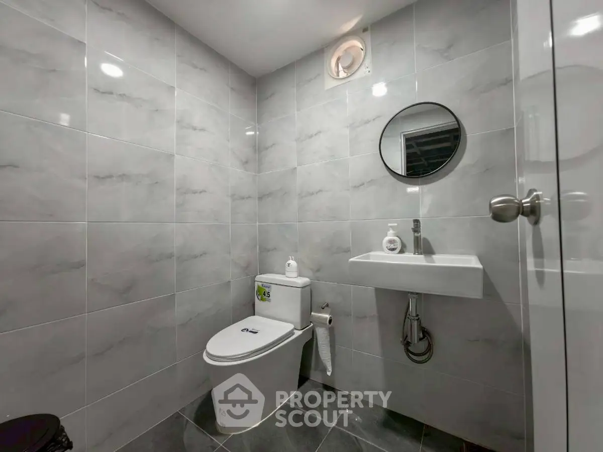 Modern bathroom with sleek gray tiles and round mirror