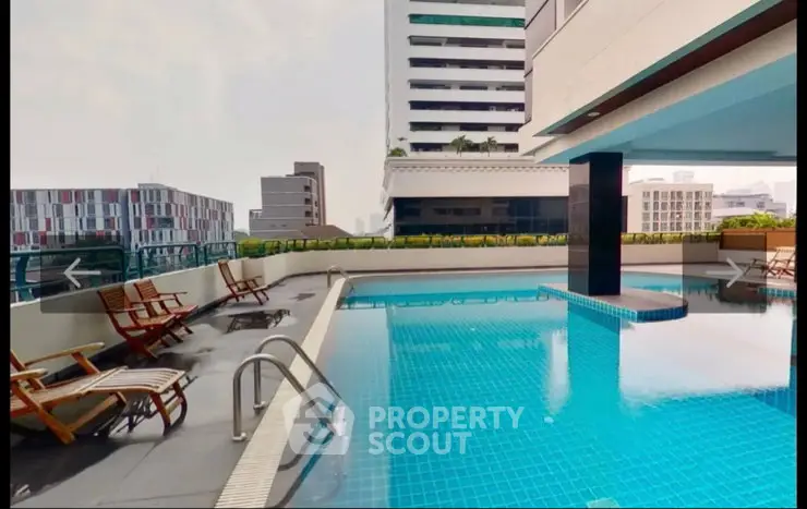 Luxurious rooftop pool with city view and modern lounge chairs in high-rise building.