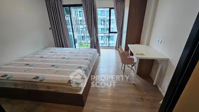 Modern bedroom with large window and study desk in a high-rise apartment.
