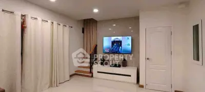 Modern living room with TV and elegant staircase in stylish home interior.