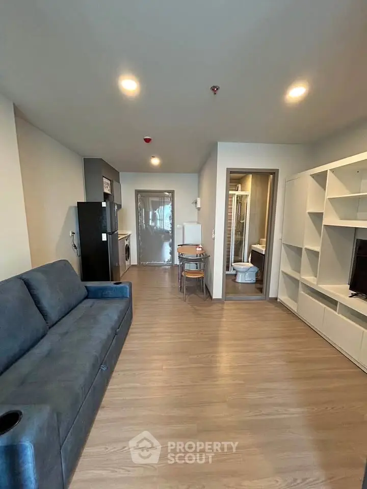 Modern living room with sleek furniture and open layout, featuring a cozy sofa and stylish shelving unit.