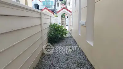 Charming exterior pathway with gravel and lush greenery leading to a picturesque entrance.