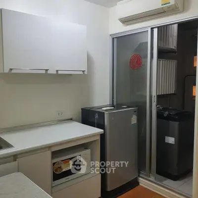 Compact kitchen with modern appliances and sleek cabinetry in a cozy apartment.