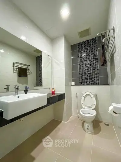 Modern bathroom with sleek design, featuring a large mirror and stylish tile accents.