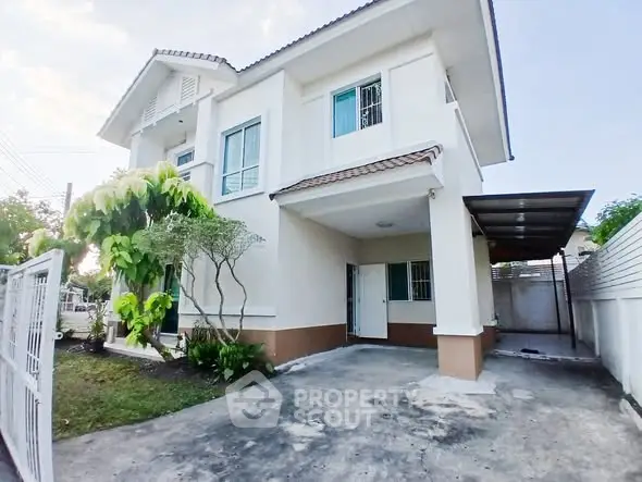 Charming two-story house with carport and lush greenery in a serene neighborhood.