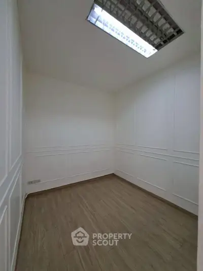 Spacious empty room with elegant wood flooring and modern lighting, perfect for customization.