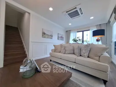 Elegant living room with cozy sofa, stylish decor, and natural light from large window.