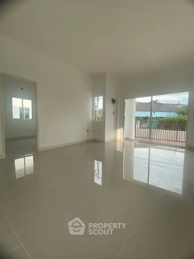 Spacious empty living room with glossy tiled floors and large windows for natural light.