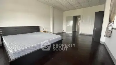 Spacious bedroom with dark wood flooring and modern minimalist design