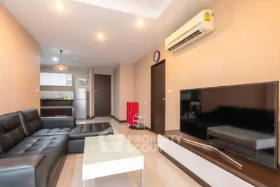 Modern living room with sleek black leather sofa and open kitchen layout