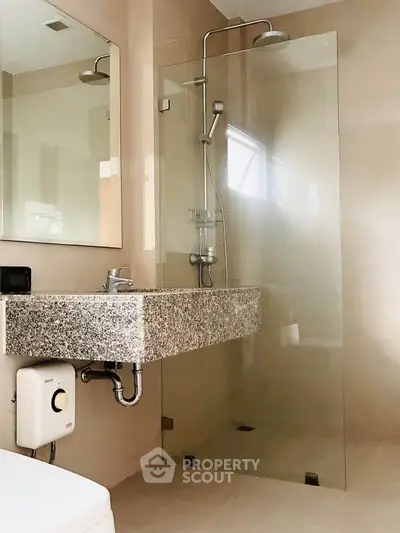 Modern bathroom with sleek glass shower and granite sink in contemporary home.