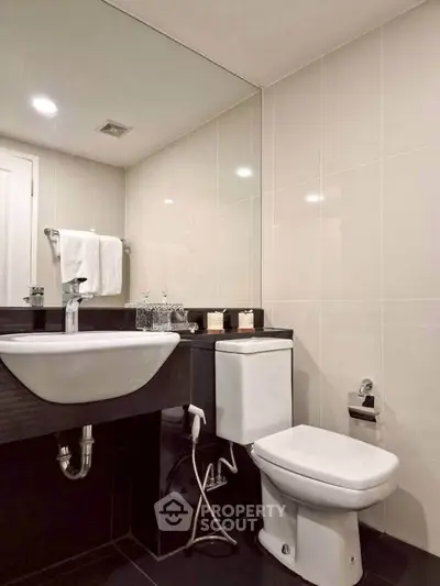 Modern bathroom with sleek fixtures and large mirror in a contemporary home.