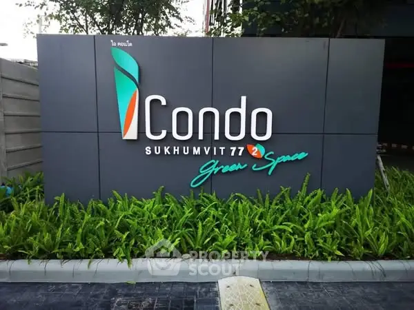 Modern condo entrance sign with lush greenery at Sukhumvit 77.