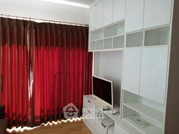 Modern living room with sleek white cabinetry and red curtains, perfect for stylish urban living.