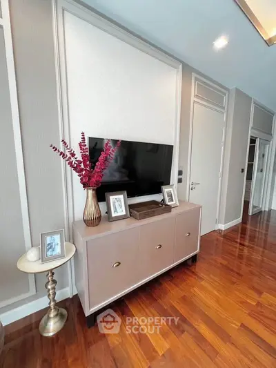 Elegant living room with modern decor and wooden flooring, featuring a stylish TV console and decorative accents.