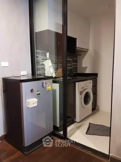 Compact kitchen with modern appliances including washing machine and fridge, sleek cabinetry, and stylish backsplash.