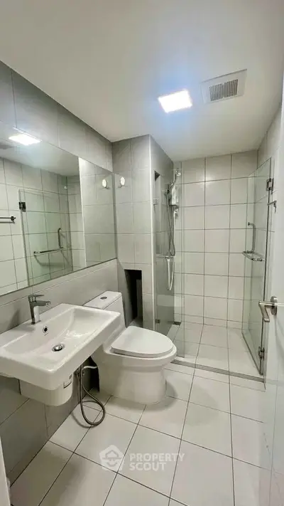 Modern bathroom with sleek design, featuring a glass shower and contemporary fixtures.
