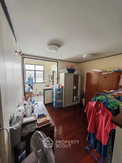 Cozy bedroom with wooden flooring and ample storage space, featuring a wardrobe and clothes rack.