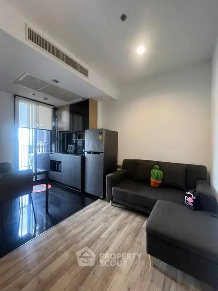Modern living room with sleek kitchen and cozy seating area, perfect for urban living.
