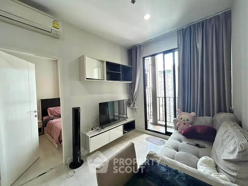 Modern living room with balcony view, stylish furniture, and cozy ambiance in a high-rise apartment.
