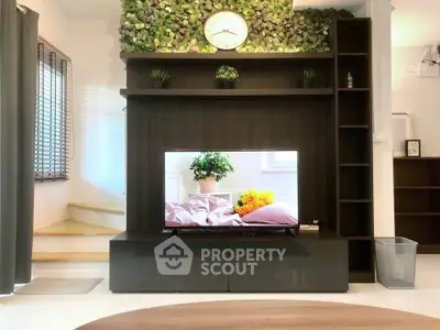 Modern living room with stylish TV unit and green wall decor