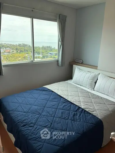 Cozy bedroom with a stunning view, featuring a neatly made bed and large window.