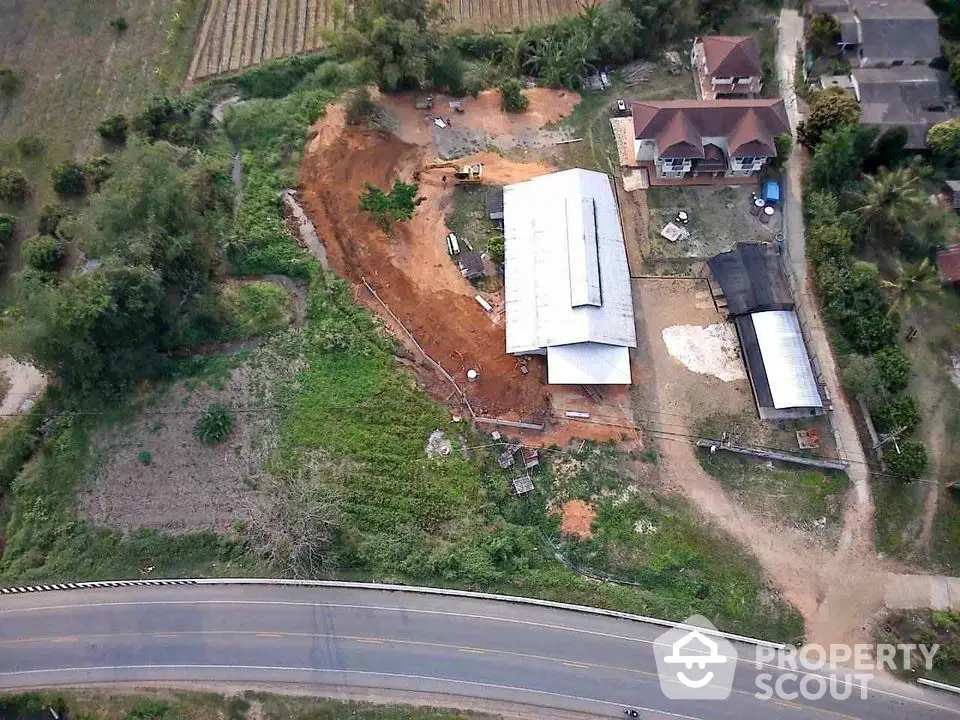 Aerial view of rural property with large building and surrounding greenery.