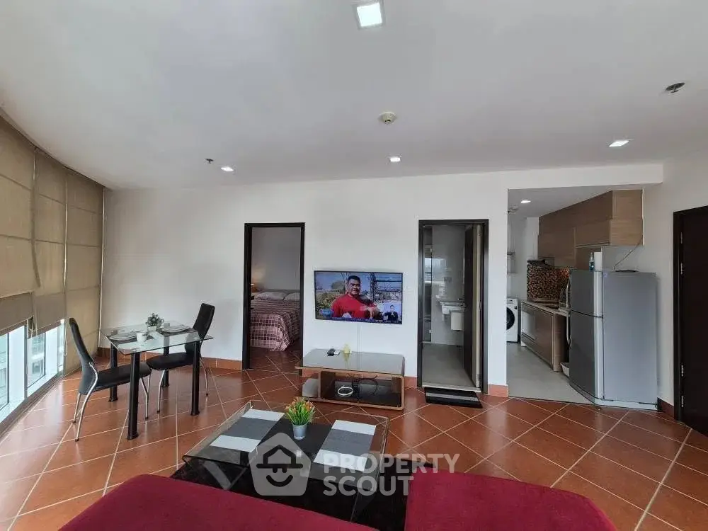 Spacious modern living room with open kitchen and dining area, featuring sleek furniture and natural light.