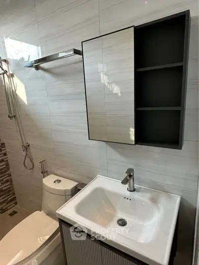 Modern bathroom with sleek fixtures and stylish wall tiles, featuring a compact sink and toilet.