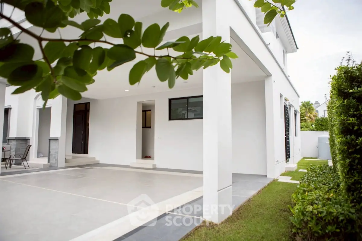Modern white exterior with spacious covered patio and lush greenery.