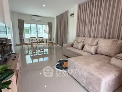 Spacious modern living room with plush sofa and dining area, featuring large windows and elegant curtains.
