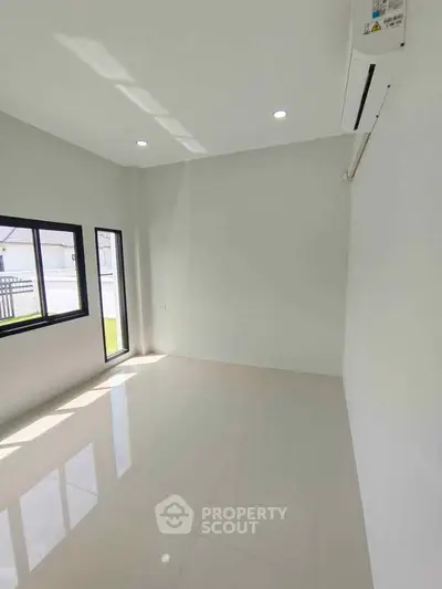 Bright empty room with large windows and air conditioning, perfect for customization.