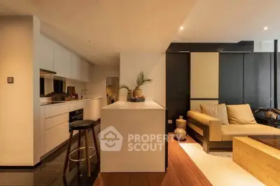 Modern open-layout kitchen and living room with sleek design and warm lighting.
