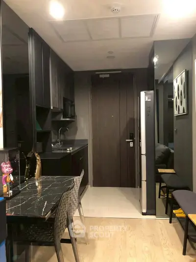 Modern kitchen with sleek black cabinetry and marble dining table in stylish apartment.