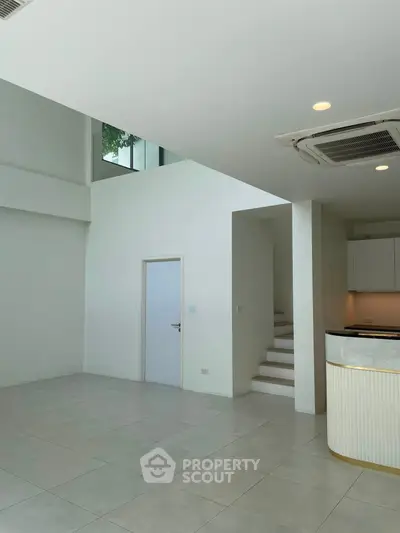 Spacious modern interior with high ceilings and sleek kitchen design, perfect for contemporary living.