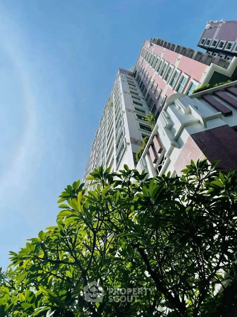 Stunning high-rise building with lush greenery and clear blue sky