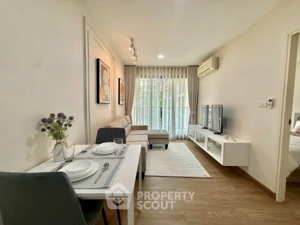 Modern living room with stylish decor and natural light, featuring a cozy dining area and sleek entertainment setup.