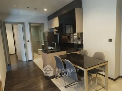 Modern kitchen with sleek black countertops and dining area in open layout apartment.