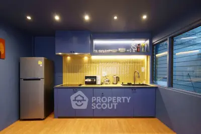 Modern kitchen with blue cabinets, stainless steel appliances, and warm lighting.