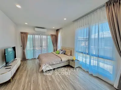 Spacious bedroom with large windows and modern decor, featuring a cozy bed and stylish flooring.