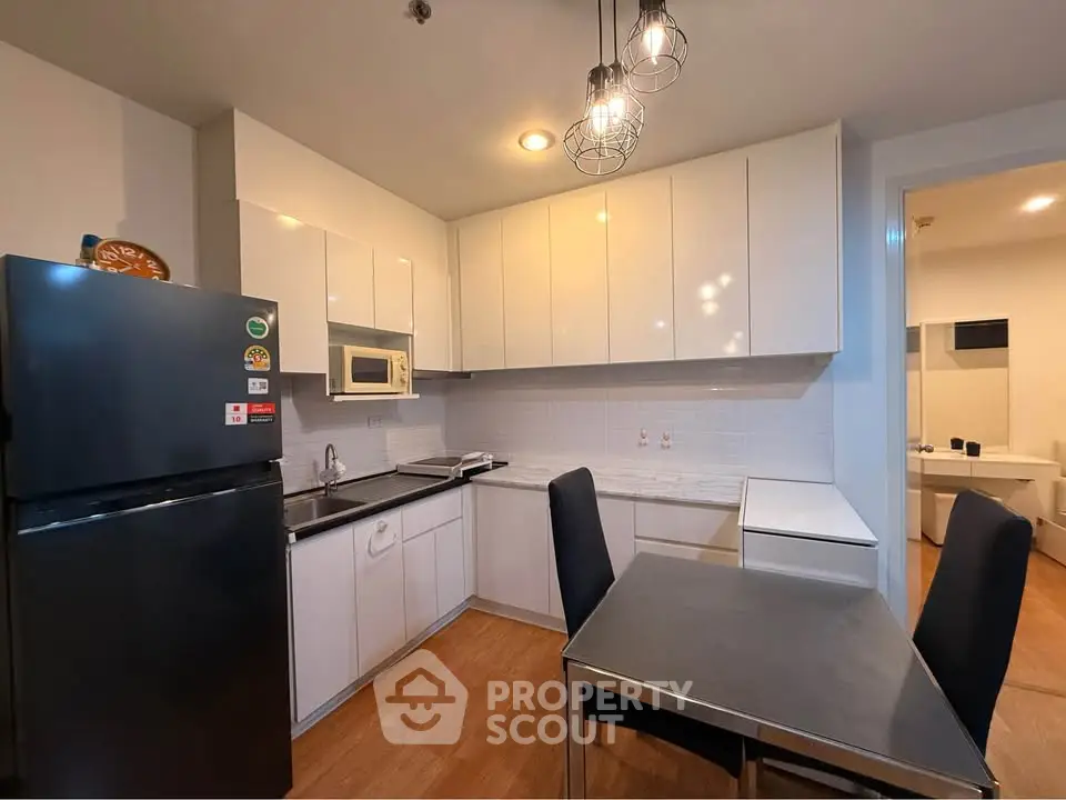 Modern kitchen with sleek white cabinets and stainless steel appliances in a cozy apartment.