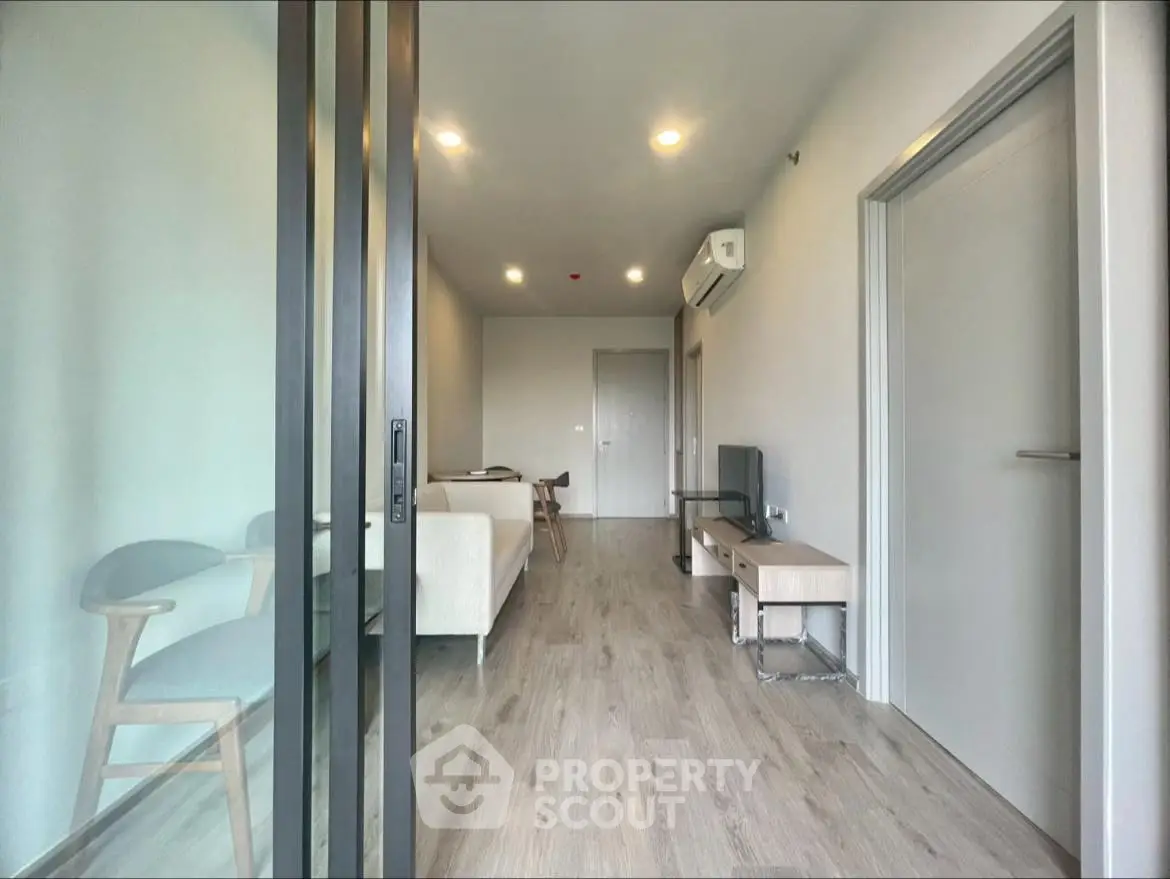 Modern living room with sleek design and wooden flooring, featuring a cozy seating area and air conditioning.