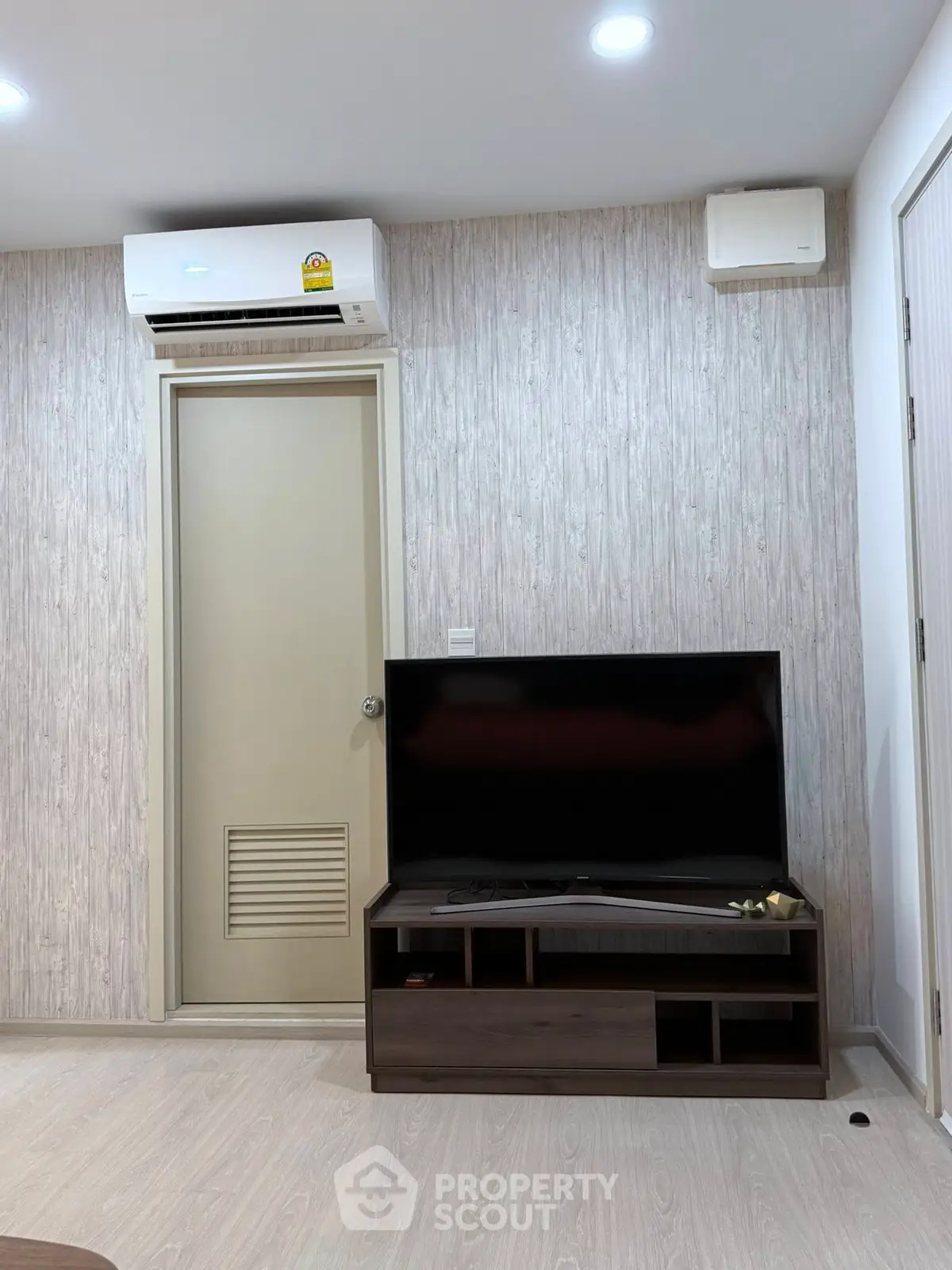 Modern living room with sleek TV setup and air conditioning unit